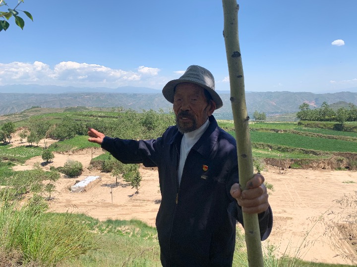 李洪占給記者展示他曾種過的樹。新華社記者李琳海攝