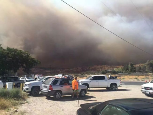 從拉斯維加斯回洛杉磯的中國游客在15號公路附近休息站休息,看得見濃煙蔽日。(美國《世界日報》)